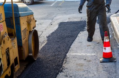 Asfalt kaldırımındaki ağır titreşimli paten sıkıştırıcısı yol onarımı için çalışıyor