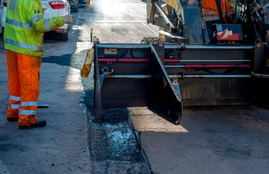 asfalt finişer makine yol yapımı sırasında işletim ve onarma işçi çalışıyor