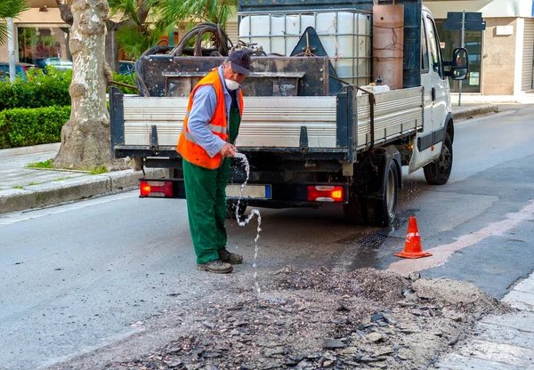 工人把水倒在磨碎的沥青路面上 用于城市街道的修理工作 — 图库照片