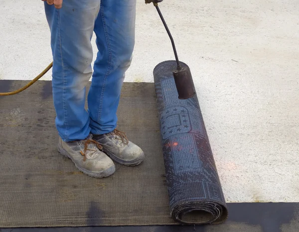 Arbetare förbereder en del av bitumen tak filt rulle för smältning med gasvärmare fackla lågan — Stockfoto