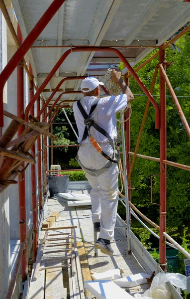 Sicherheit am Arbeitsplatz. Arbeiter baut ein Gerüst auf — Stockfoto