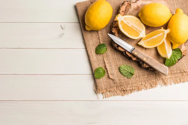 Skivor, halv saftiga citron med myntablad och kniv på den — Stockfoto