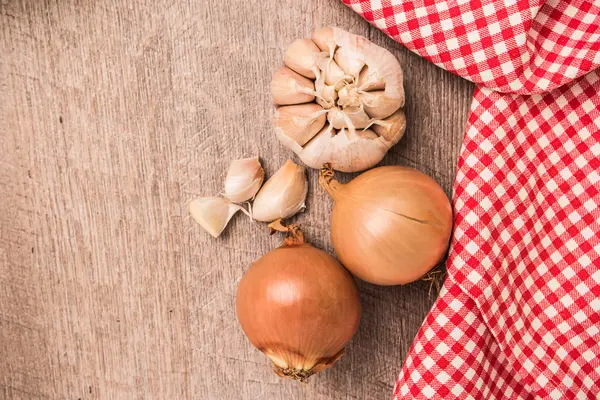 Frisches Gemüse aus dem Garten, Knoblauch und Zwiebeln auf einem Holztisch — Stockfoto