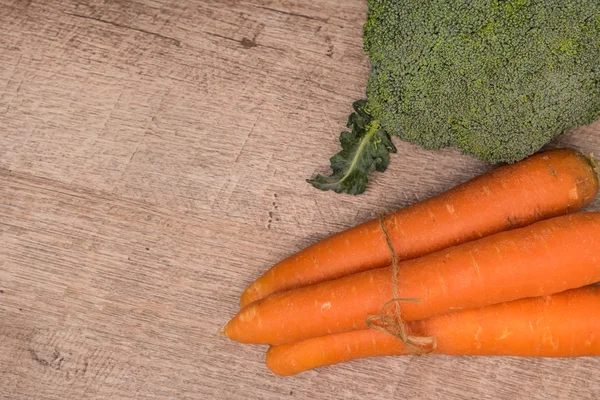 Verse groenten uit de tuin, wortelen en broccoli op een hout — Stockfoto