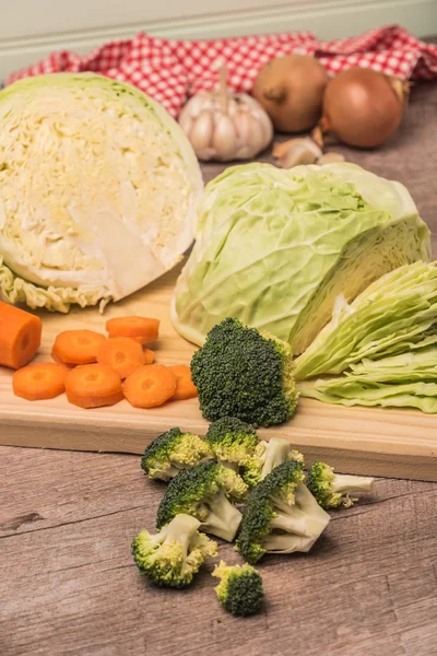 Verse groenten uit de tuin, wortels, kool, broccoli, ui en knoflook op een houten tafel — Stockfoto