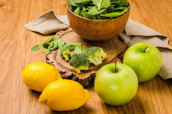 Foglie di spinaci primaverili nella ciotola, broccoli, limoni e mele — Foto Stock