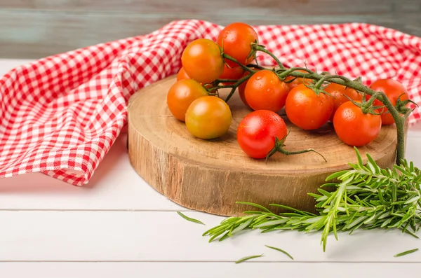 Organic cherry tomatoes with rosemary on rustic wooden table — Stock Photo, Image