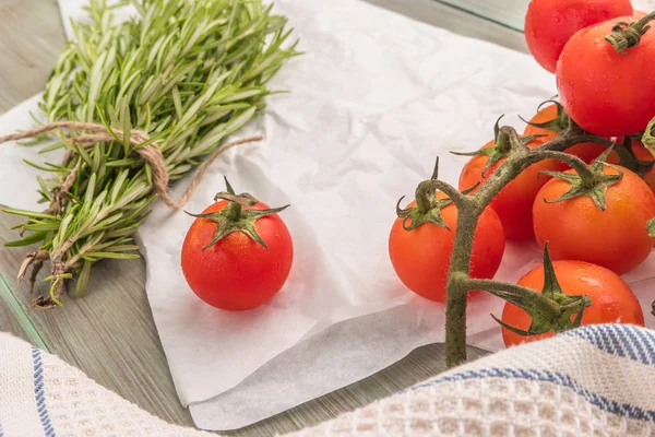 Organic cherry tomatoes with rosemary on wrinkled paper — Stock Photo, Image