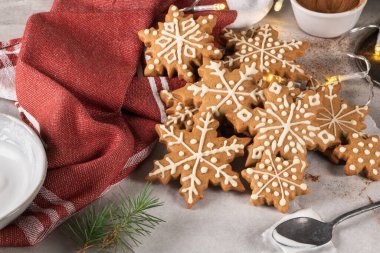 Tezgahta kremalı zencefilli kurabiyeler ve şenlikli ışıklar. Noel kurabiyeleri şekerle süslenmiş kar taneleri. Noel tatili geleneği ve gelişimi