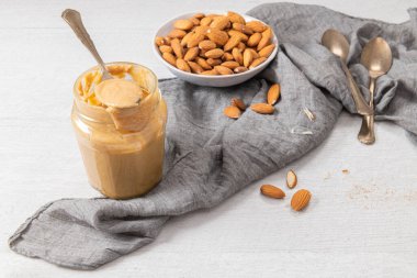 Badem ezmesi, badem ezmesinden yapılmış çiğ gıda ezmesi fındık ezmesi, çıtır çıtır ve karıştırılmış, beyaz ahşap masa, kopyalama alanı