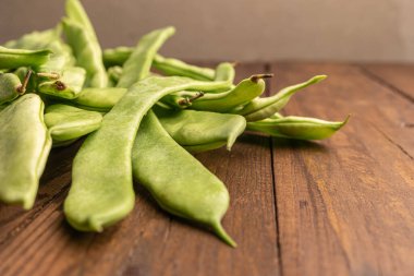 Çiğ yeşil fasulye yakın plan. Taze yeşil fasulye olarak da bilinir. Fasulye, fasulye, fasulye, mısır gevreği ve taricotlar ahşaba dönüşür.