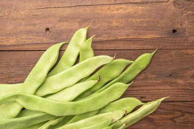 Çiğ yeşil fasulye yakın plan. Taze yeşil fasulye olarak da bilinir. Fasulye, fasulye, fasulye, mısır gevreği ve taricotlar ahşaba dönüşür.
