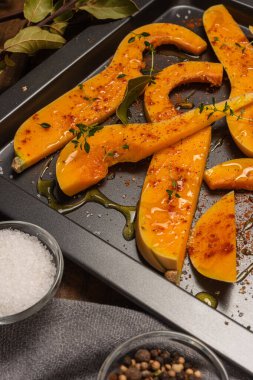 Fırında pişirmek için hazırlanmış bir sürü parlak balkabağı dilimi..