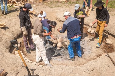 AMARANTE, PORTUGAL - CRCA APRIL 2022: 2022 Nisan 2022 'de Portekiz' in Amarante şehrinde Gondar 'ın kara kilinin ateşleme işlemi sırasında şenlik ateşinin közlerinin üzerine kil parçaları istiflemek.