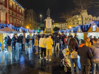 Porto, Portekiz - 9 Aralık 2023. Batalha Meydanı 'nda sıcacık bir noel pazarı, her zamanki gibi el işi ve yiyecek satıyor. Sıcak ışıklar ve tatil süslemeleriyle süslenmiş oyalama, ziyaretçiler yakınlarda gezinirken mevsimin şenlikli ruhunu yakalıyor..