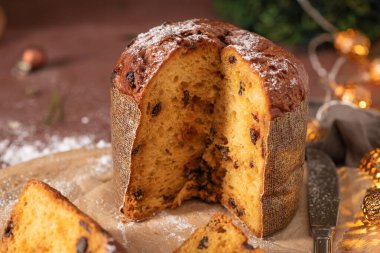 Tüm Panettone 'un aşırı yakın plan çekimleri altın, havadar ve zengin kuru üzümlü hamurunu sergiliyor. Tatiller için toz şekerle güzelce tozlanmış.