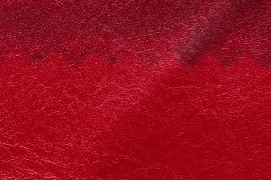 Deri bir yüzeyin yatay tam çerçeve makrosu canlı kırmızıdan koyu bir bordo tonuna geçerek tahılları renklendiriyor.