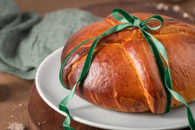 Paskalya masasında yumurtasız, yeşil kadife kurdeleli geleneksel Portekiz Paskalya pastası.