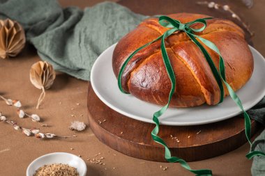 Paskalya sofrasında yumurtasız Portekiz geleneksel Paskalya pastası Folar yeşil kurdeleli ve rezene tohumlu küçük kaseli.