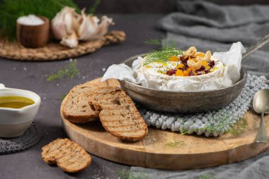 Renkli kurutulmuş kayısı, kızılcık ve kaju fıstığı ile kaplanmış kremalı peynirin detaylı bir görüntüsü, ahşap ahşap bir sette ızgara zanaatkar ekmeği ile servis edilir.