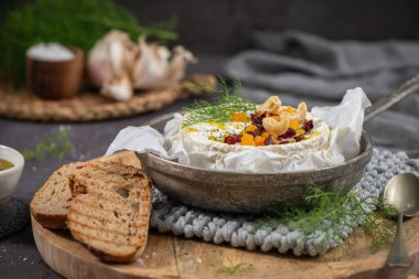 Kurutulmuş kayısı, kızılcık ve kaju fıstığı ile kaplı, sıcak ve rahat ahşap bir tabakta kızartılmış rustik ekmek dilimleri ile servis edilen lüks bir peynirli Camembert peyniri.