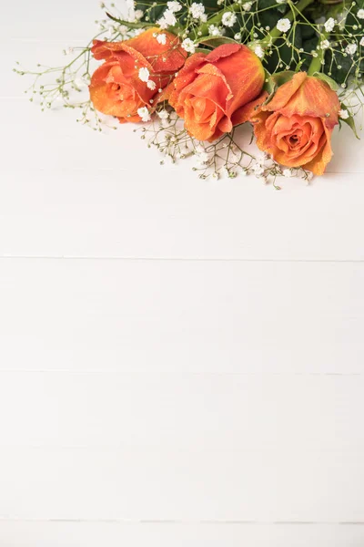 Ein Strauß orangefarbener Rosen und Zigeunerblumen auf einem Holztisch. Kopierraum — Stockfoto