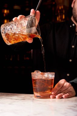Lokantada ya da barda kırmızı Negroni alkollü kokteyli. Barmen limon sıkma, içecek fotoğrafçılığı hazırlıyor.