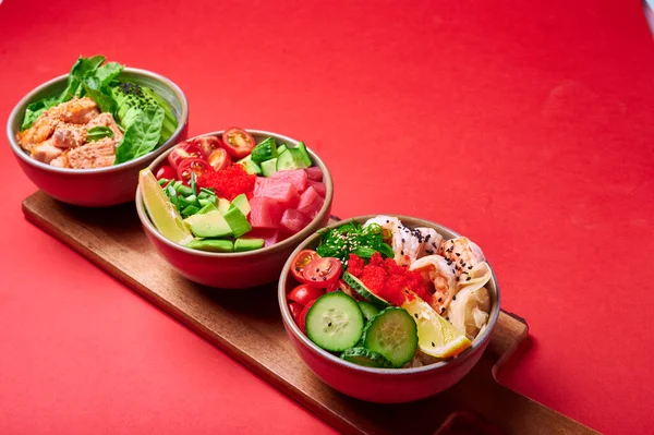 Set of fresh poke bowl with salmon, avocado, chukka, basil,shrimp and smoked fish on red background with place for text — Stock Photo, Image