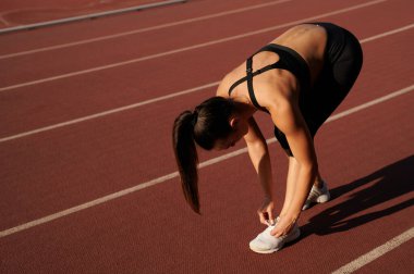 Stadyumdaki sporcu kadın bağcıklarını bağlıyor