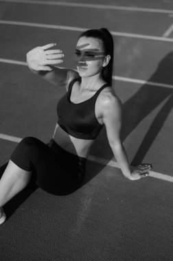 Kız stadyumdaki koşu bandında oturuyor.