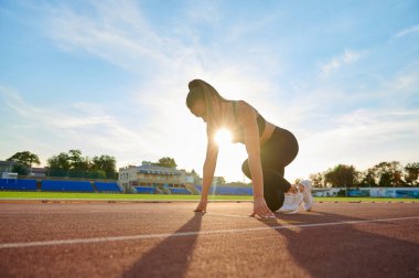 Genç sporcu kadın bir stadyumda koşuyor.
