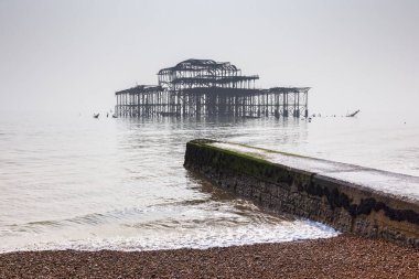 Brighton Plajı ve düz ışık, Sussex, İngiltere, İngiltere'de sisli bir günde eski Batı iskelede kalıntıları.