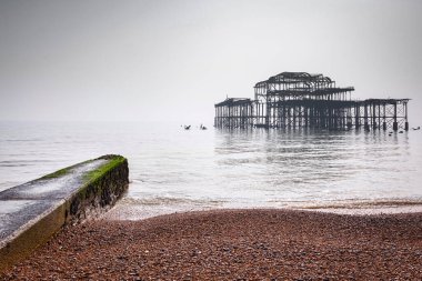 Brighton Plajı ve düz ışık, Sussex, İngiltere, İngiltere'de sisli bir günde eski Batı iskelede kalıntıları.