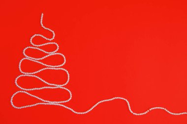 Kırmızı arka planda, Noel ağacı şeklinde beyaz inci dizisi. Metin için alanı olan düz bir düzen