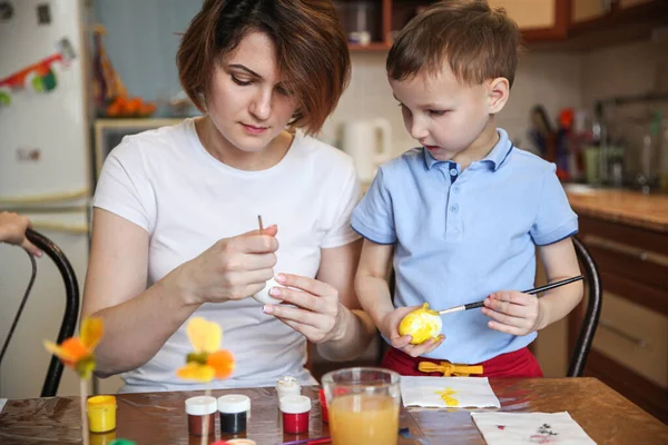 Anne ve oğul, Paskalya yumurtalarını evde mutfak masasında süslerler.