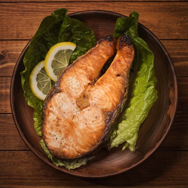 Steak de truite cuit au four en poterie avec salade et tranches de citron, vue sur le dessus — Photo