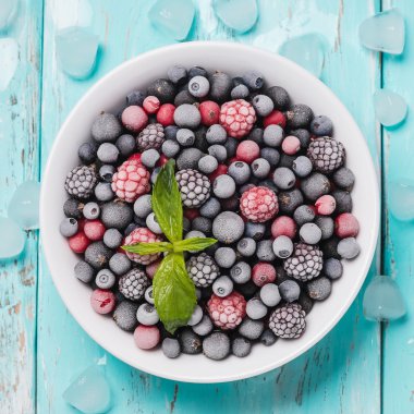 Frozen berries on a turquoise background, top view clipart