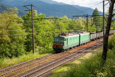 Skole, Ukrayna - 19 Haziran 2021: Ukrayna demiryollarının yük elektrikli treni VL11 yeşil orman ve dağların arka planında demiryolu üzerinde