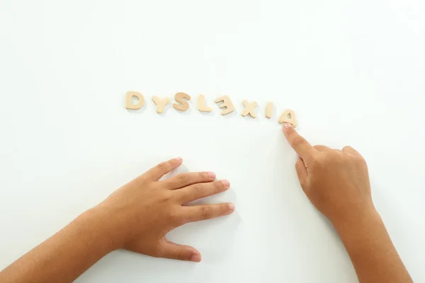 Χέρια ενός κοριτσιού που αποτελούν τη λέξη δυσλεξία με ξύλινες επιστολές — Φωτογραφία Αρχείου