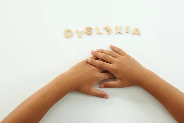 Handen van een meisje vormen het woord dyslexie met houten letters — Stockfoto