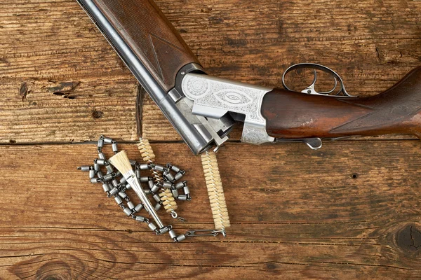 Pistola de caza con kit de limpieza en una mesa de madera — Foto de Stock