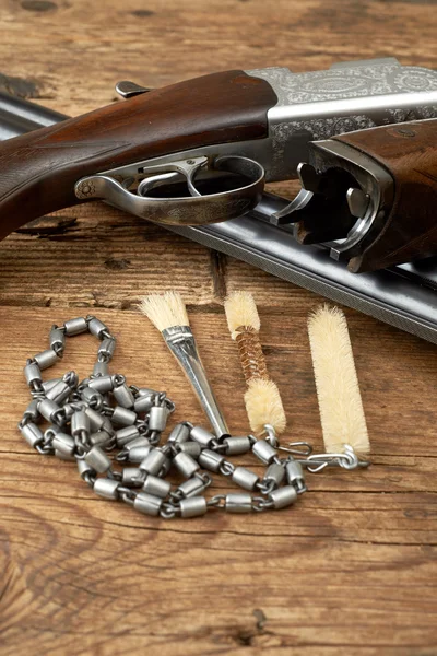 Pistola de caza con kit de limpieza en una mesa de madera — Foto de Stock