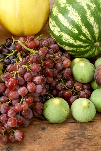 Many fresh autumn fruits on wooden kitchen table — Stock Photo, Image