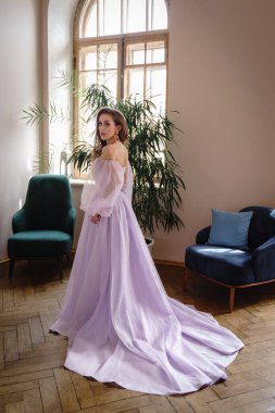 Güzel bir kadın açık mor bir elbise içinde poz veriyor, içi lüks.