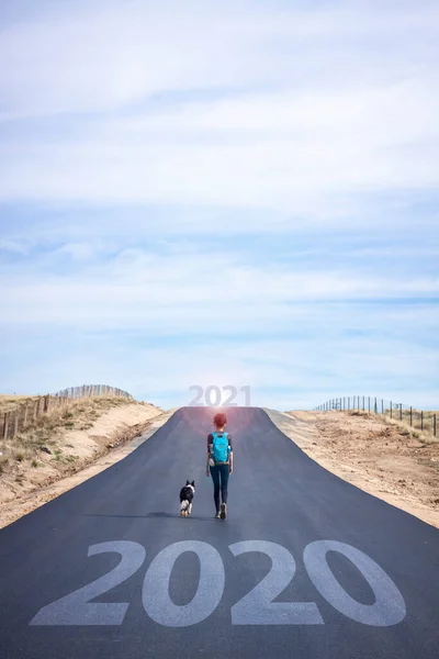 Start a new year. Leave behind 2020. Lifestyle photography, woman with dog on the road in search of adventure