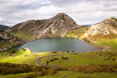 İlkbaharda Covadonga gölleri ve sis. Turistler Enol Gölü 'nde yürüyüş yapıyor. Asturias, İspanya