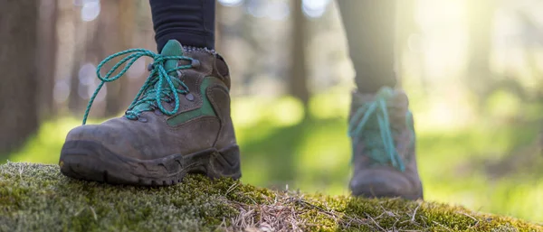 person walking through the forest in nature. Healthy life style. Boots in the foreground