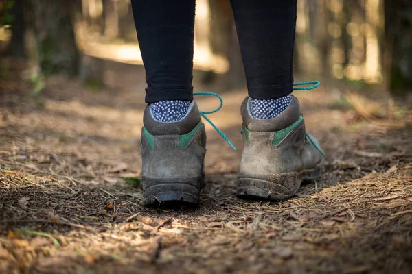 person walking through the forest in nature. Healthy life style. Boots in the foreground