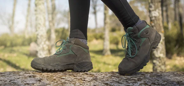 person walking through the forest in nature. Healthy life style. Boots in the foreground