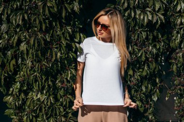 Beyaz tişört ve gözlük takan şık sarışın kız.